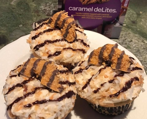 Caramel Delites Cupcakes: Toasted coconut cupcake with caramel buttercream, toasted coconut, chocolate ganache stripes and a cookie