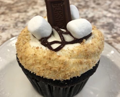Camper Cupcake: Chocolate cupcake with marshmallow buttercream, graham cracker crumbs, chocolate ganache drizzle, marshmallows and a chocolate bar
