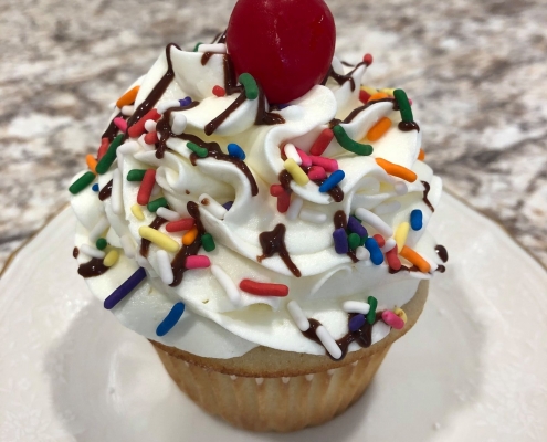 Celebration Cupcake: Vanilla cupcake with vanilla buttercream, chocolate ganache drizzle, rainbow sprinkles and a maraschino cherry
