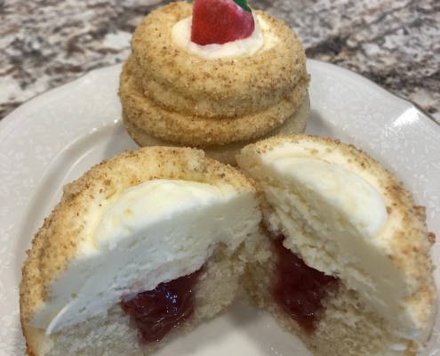 Cheesecake Cupcake: Vanilla cupcake with strawberry filling, cream cheese buttercream, graham cracker crumbs and a strawberry candy