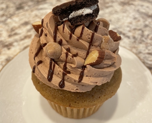 Mud Pie Cupcake: Coffee cupcake with mocha buttercream, chocolate ganache drizzle, chopped almonds, peanut butter chips and a mini Oreo cookie